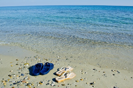 Vacation mood photo of beach shoes. Transparent clear and calm seaの写真素材