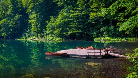 Small wooden pier and recreational boats at forest lake. Hiking routes of Biogradska gora national park, Montenegroの写真素材