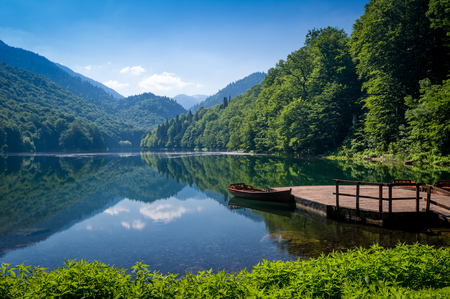 Biogradska gora national park landscape. Beautiful lake surrounded by hills and mountains with wooden pier and boats for rent. Montenegro.の写真素材
