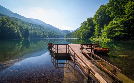 Biogradsko jezero landscape. Calm water with reflections of forest on the hills and beautiful old wooden pier. Montenegro national park.の写真素材