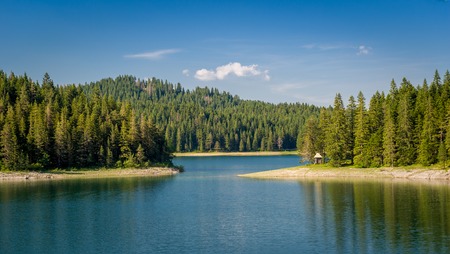 Small wooden house at the mountain lake shore. Thick coniferous forests at Black Lake, national park Durmitor, Montenegroの写真素材