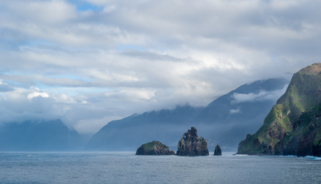 Landscape with small rocks in the water and steep shores of Madeira island near the Porto Moniz, Portugal.の写真素材