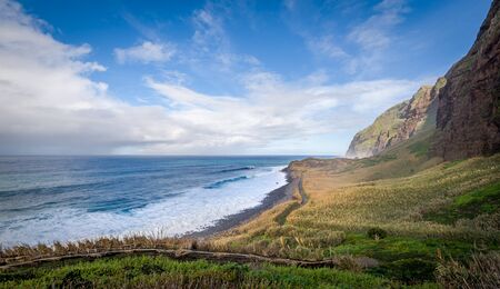 Madeira island wild bay Calhau das Achadas, popular viewing and hiking spot. Atlantic ocean, mountains and fields in sunny january day.の写真素材