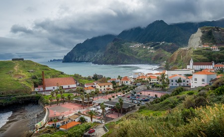Porto da Cruz town in the north shore of Madeira island in stormy weather with mountain range in the heavy clouds. Madeira, Portugal.の写真素材