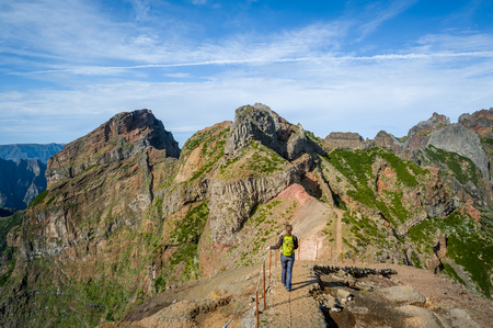 Woman hiker on the dangerous path between the rocky cliffs of Pico Arieiro hiking path. Madeira island, Portugal.の写真素材