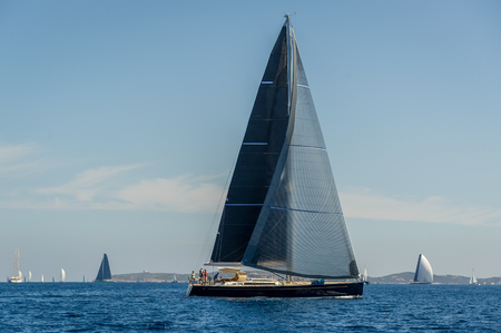 Luxury big sailing yacht with black sails horizontal photo. Sardinia, Italy.の写真素材