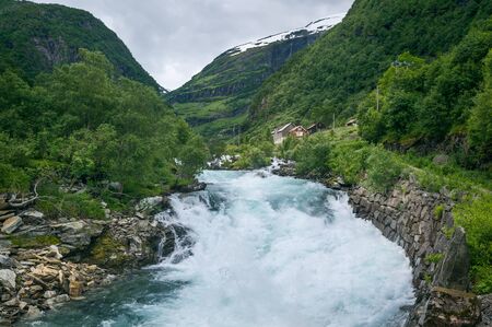 Norwegian rural landscape with fast mountain river and village house. Flam, Norway.の写真素材