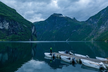 Night landscape of Geiranger fjord with lonely fisherman on the pier. Geirangerfjord, Norway.の写真素材