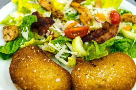 Traditional caesar salad with grilled chicken Bacon Stripes and salted garlic breadの写真素材