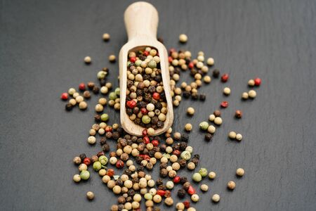 Many peppercorns and a wooden spoon