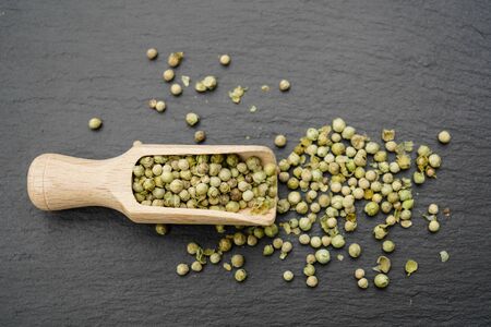 Green peppercorns and a wooden spoon
