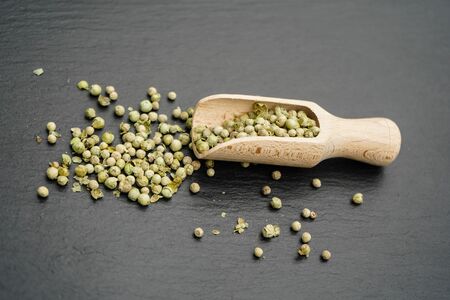 Green peppercorns and a wooden spoonの写真素材
