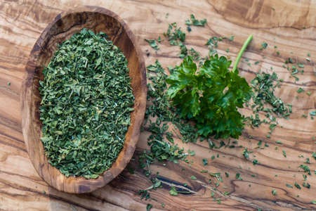 dried rubbed and fresh parsley on olive woodの写真素材