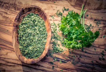 dried rubbed and fresh parsley on olive woodの写真素材