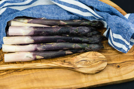 purple Asparagus officinalis a seasonal vegetable on olive woodの写真素材