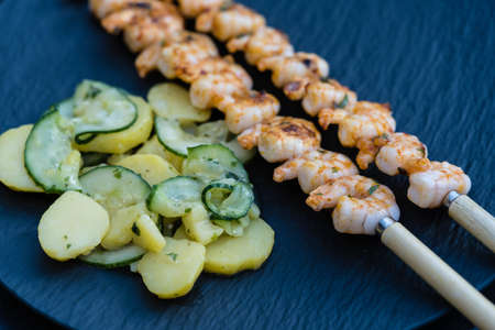 Spicy white tiger prawns from the grill with potato cucumber saladの写真素材