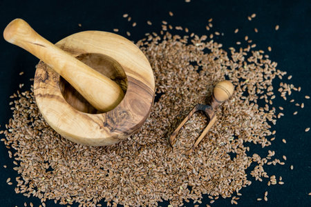 a pile of flaxseeds and utensils made of olive woodの写真素材
