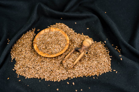 a pile of flaxseeds and utensils made of olive wood