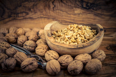 Fresh and cracked walnuts on olive wood
