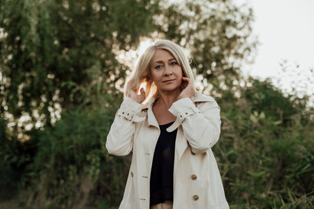 Portrait of a beautiful blonde woman in a white coat on the nature.の写真素材