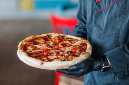 pizza in the hands of a delivery man in black gloves.の写真素材