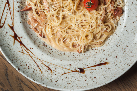 Spaghetti carbonara with bacon and tomato on a white plate.の写真素材