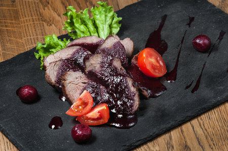 beef tongue served with cranberry sauce on a black slate plateの写真素材