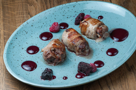 chicken rolls with berry sauce on a blue plate on a wooden tableの写真素材