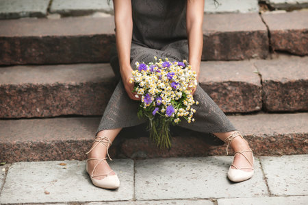 Beautiful girl in a gray dress with a bouquet of flowersの写真素材