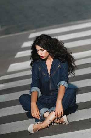 beautiful brunette girl in jeans overalls on zebra crossingの写真素材
