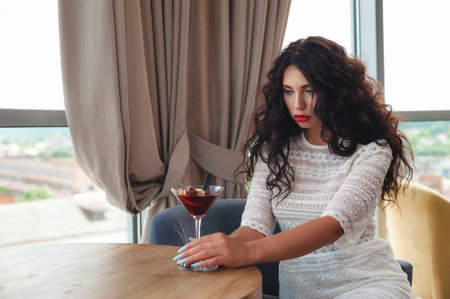 Beautiful young woman sitting in a cafe and drinking red wine.の写真素材