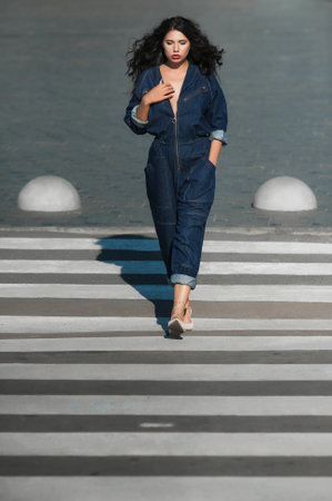 Beautiful young woman walking on zebra crossing in the city.の写真素材