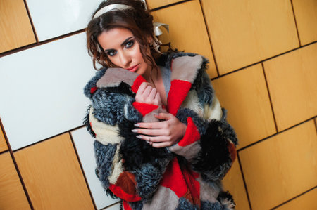 Portrait of a beautiful girl in a fur coat and a scarfの写真素材