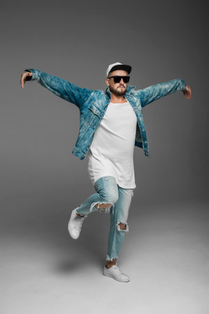 stylish hipster man in sunglasses and cap dancing on gray backgroundの写真素材