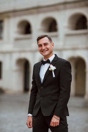 groom in a black suit with a bow tie on his wedding dayの写真素材