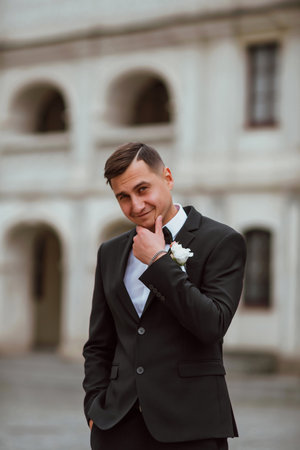 groom in a black suit on the background of the old castleの写真素材