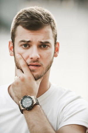 Portrait of handsome young man in white t-shirt and wristwatch