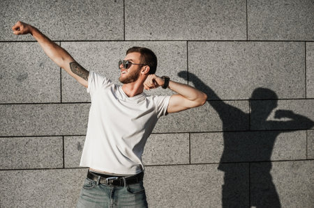 Handsome young man in sunglasses and t-shirt dancing on the streetの写真素材