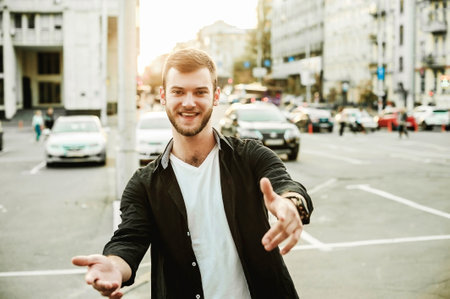 Young handsome hipster man with beard in black jacket and white t-shirt walking on the street.