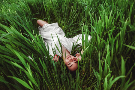 Young woman lying on green grass in the field. top view.の写真素材