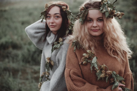 Two beautiful young women with wreaths on their heads in the field