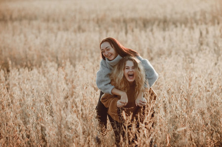 Two redhead women in warm sweaters walking in wheat field.の写真素材