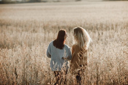 Two beautiful girls walk in a wheat field. They hug and laugh.の写真素材