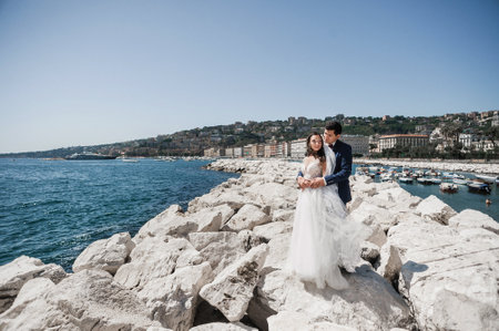 Beautiful wedding couple, bride and groom posing on the rocks near the seaの写真素材