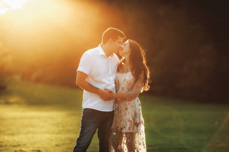 Beautiful young couple in love embracing in the park at sunset.の写真素材