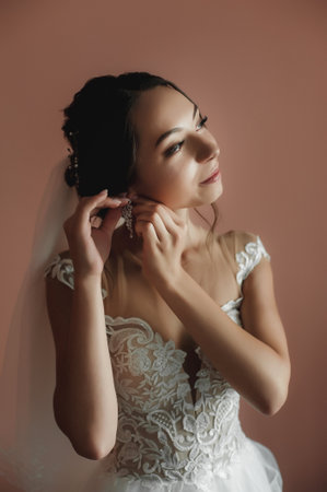 Portrait of a beautiful bride in a white wedding dress on a pink background