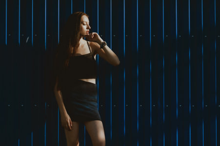 Portrait of a young beautiful girl in a black dress with a microphone.の写真素材