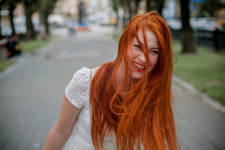 Portrait of a beautiful redhead girl with long hair on the street.の写真素材