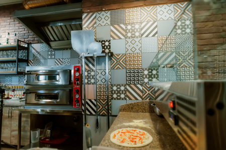Pizza tools hang on the wall next to the oven. Cafe interior. Multicolored tile for room decoration. Pizza place.の写真素材