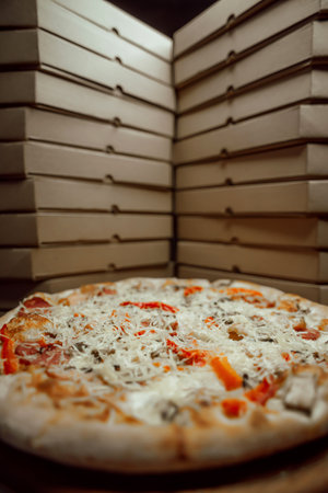 Many cardboard boxes of pizza. The boxes are on top of each other with one pizza between them.の写真素材